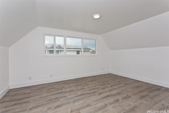 bonus room featuring vaulted ceiling, baseboards, and wood finished floors