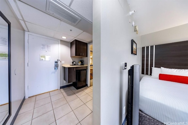 bedroom featuring baseboards, visible vents, a drop ceiling, and light tile patterned flooring