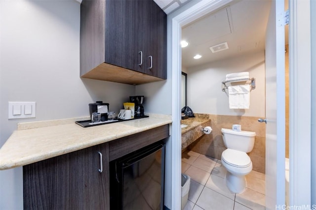 interior space featuring visible vents, wainscoting, toilet, tile patterned flooring, and tile walls