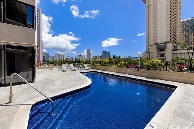 pool featuring a city view, a patio, and fence