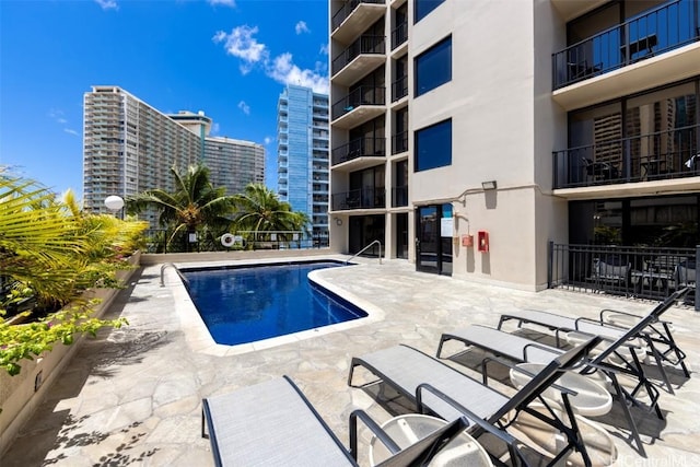 pool with a patio area and a city view