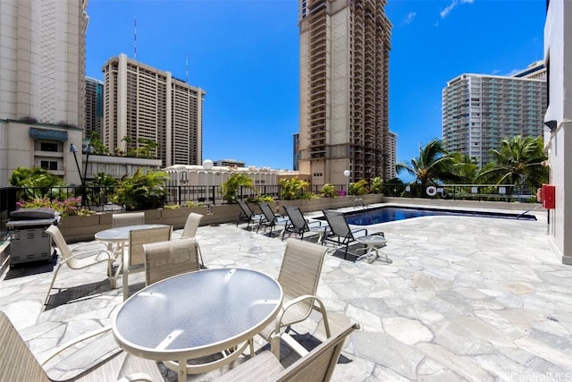 community pool with a view of city, a patio, outdoor dining area, and a grill