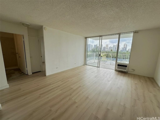 spare room with a wall of windows, a city view, a textured ceiling, and wood finished floors