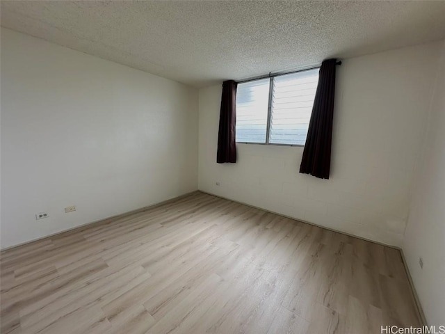 empty room featuring a textured ceiling and light wood finished floors