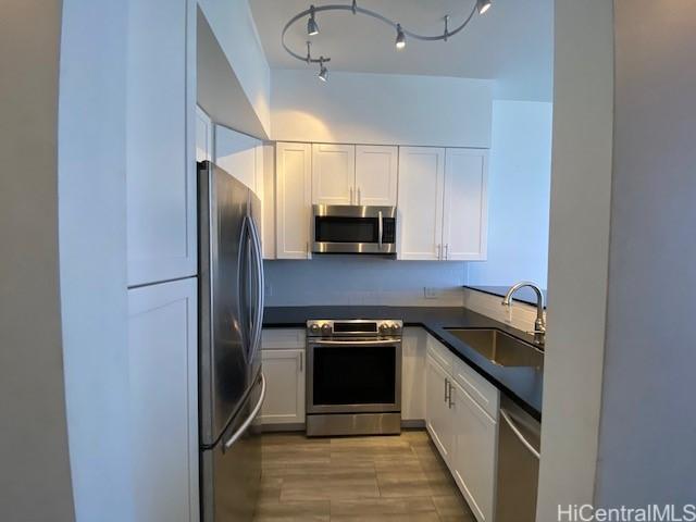 kitchen featuring a sink, stainless steel appliances, dark countertops, and white cabinets