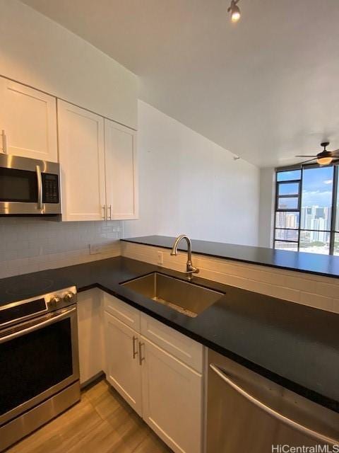 kitchen featuring a sink, stainless steel appliances, backsplash, and white cabinetry