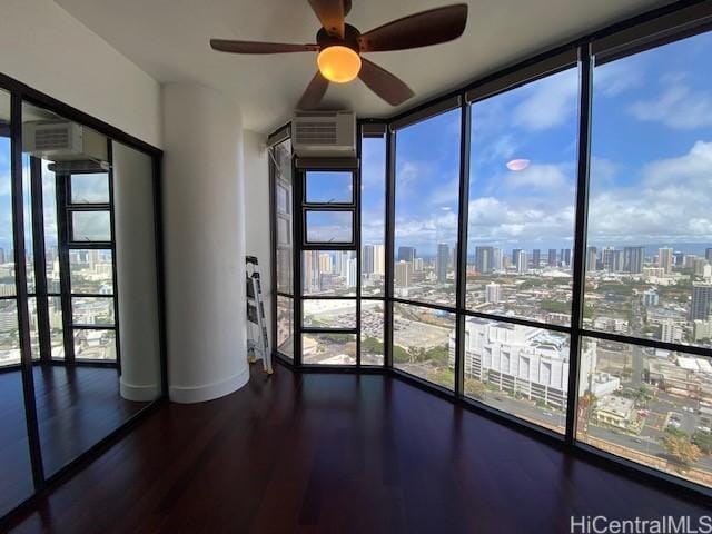 interior space featuring a city view, floor to ceiling windows, a wall unit AC, wood finished floors, and a ceiling fan