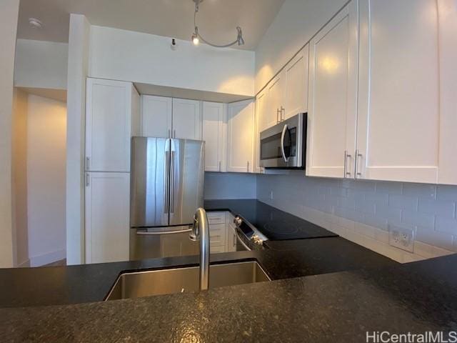 kitchen with decorative backsplash, white cabinetry, stainless steel appliances, and a sink