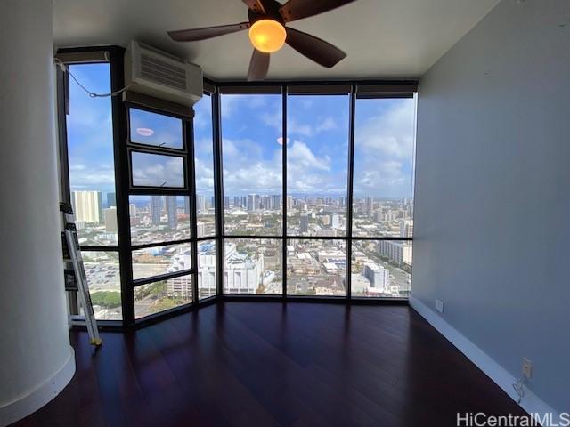 unfurnished sunroom with a view of city, ceiling fan, and a wall mounted AC