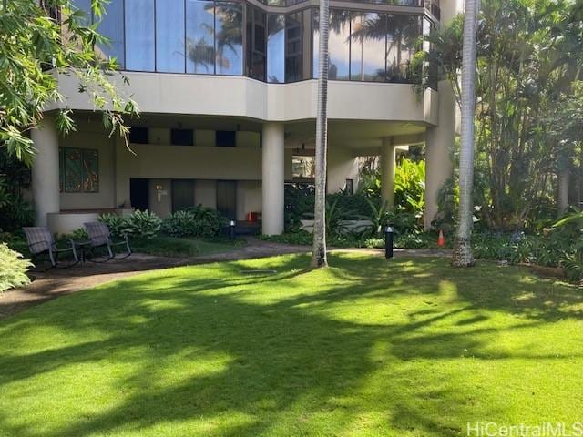 rear view of property featuring a lawn and stucco siding