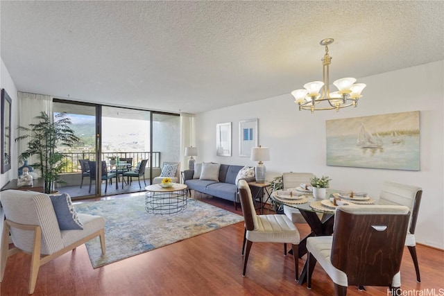 dining space featuring a textured ceiling, a wall of windows, wood finished floors, and an inviting chandelier