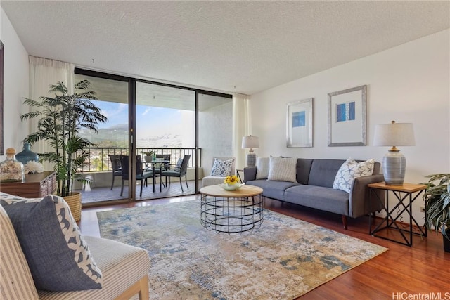 living area with floor to ceiling windows, a textured ceiling, and wood finished floors