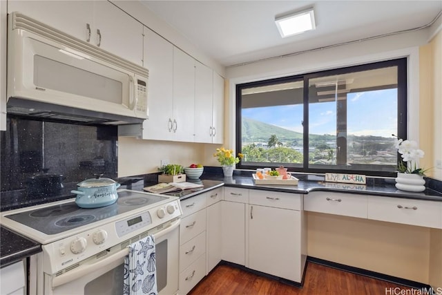 kitchen featuring white appliances, tasteful backsplash, dark countertops, dark wood-type flooring, and white cabinetry