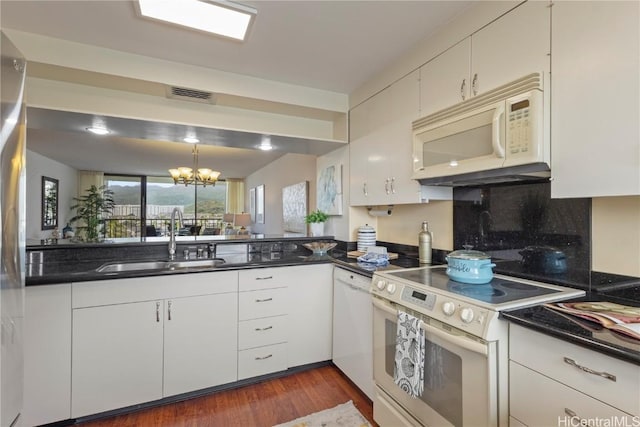 kitchen with white appliances, visible vents, dark countertops, a chandelier, and a sink