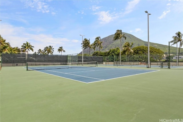 view of tennis court with fence and a mountain view