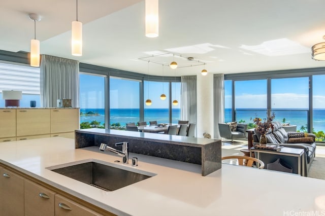 kitchen with a water view, rail lighting, light countertops, pendant lighting, and a sink