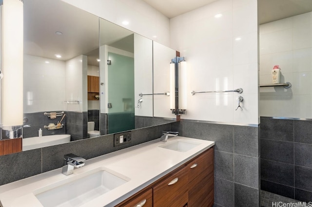 full bath featuring double vanity, a sink, tile walls, and a shower stall