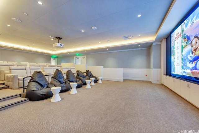 home theater room featuring a tray ceiling, visible vents, and light carpet