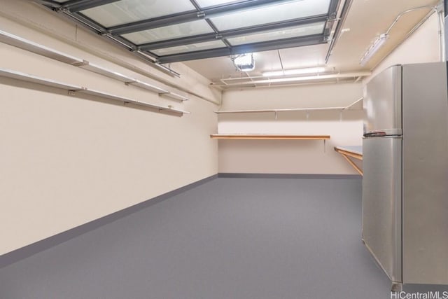 garage with baseboards, a garage door opener, and freestanding refrigerator