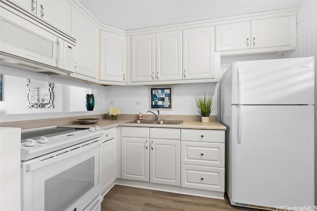 kitchen with white appliances, wood finished floors, a sink, white cabinets, and light countertops