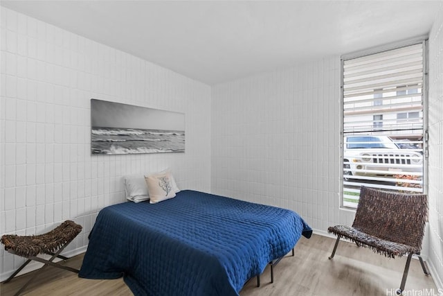 bedroom featuring tile walls and wood finished floors