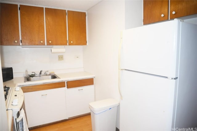 kitchen featuring washer / clothes dryer, light countertops, freestanding refrigerator, a sink, and black microwave