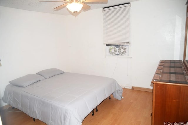 bedroom with ceiling fan, wood finished floors, and baseboards