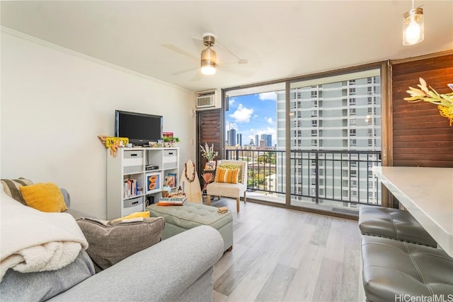 living area with crown molding, a wall of windows, a wall unit AC, and wood finished floors