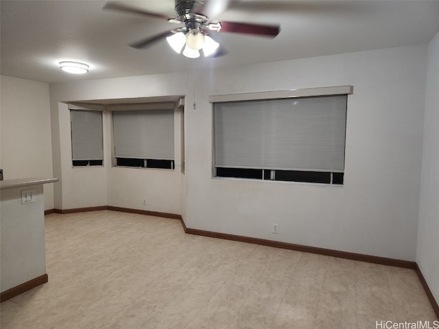 spare room with a ceiling fan and baseboards