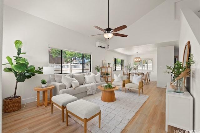 living room with a ceiling fan, baseboards, high vaulted ceiling, a wall mounted AC, and light wood-style flooring