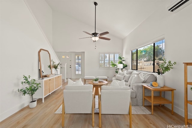 living area featuring an AC wall unit, light wood-style floors, baseboards, and high vaulted ceiling