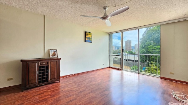 spare room featuring expansive windows, wood finished floors, baseboards, and a view of city