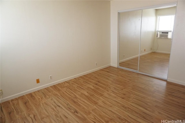 unfurnished bedroom with light wood finished floors, a closet, cooling unit, and baseboards