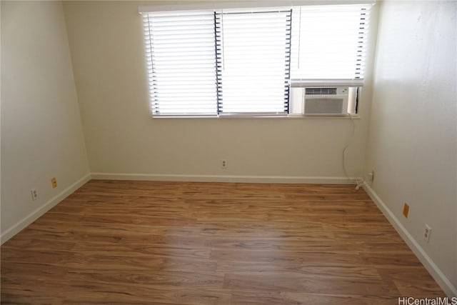 empty room with cooling unit, wood finished floors, and baseboards