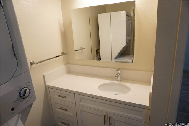 bathroom featuring stacked washer / dryer and vanity