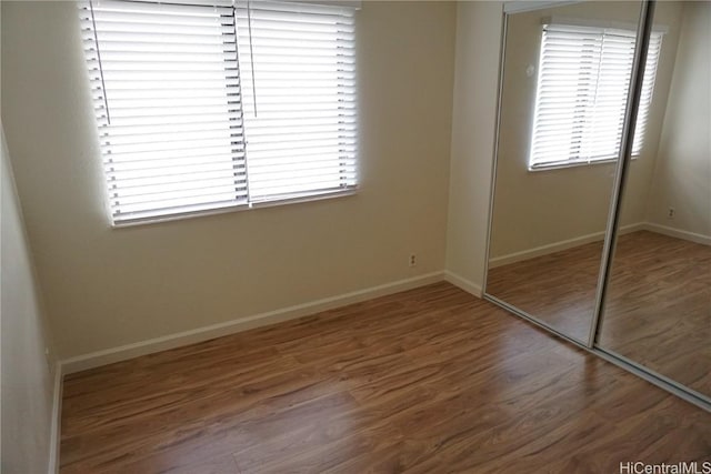 unfurnished bedroom featuring a closet, wood finished floors, and baseboards