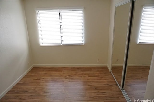 unfurnished bedroom with a closet, wood finished floors, and baseboards