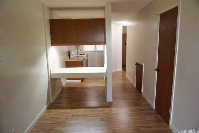 corridor with wood finished floors, a sink, and baseboards