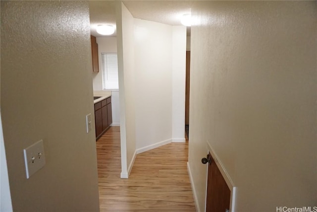 hall with baseboards and light wood finished floors