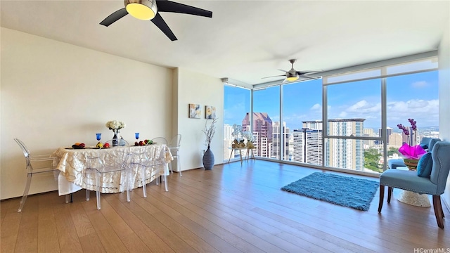 interior space featuring a city view, hardwood / wood-style floors, ceiling fan, and a wall of windows