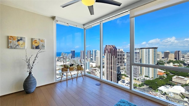 sunroom / solarium featuring a city view, plenty of natural light, and ceiling fan