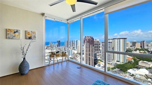 sunroom featuring a wall of windows, hardwood / wood-style floors, and a view of city