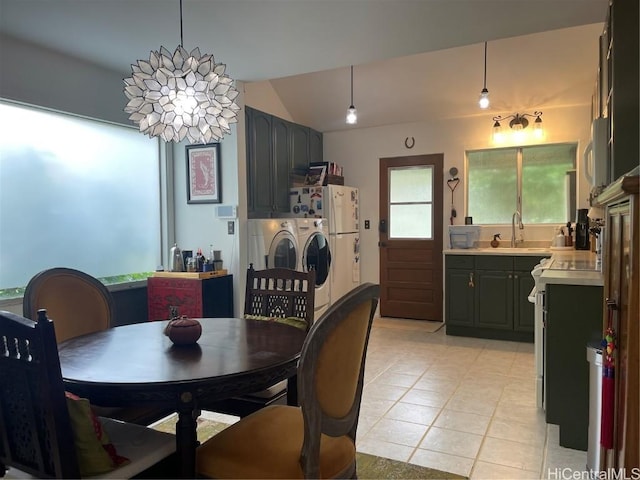 dining space with washer and dryer, lofted ceiling, and light tile patterned floors