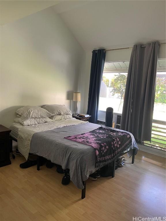 bedroom with multiple windows, vaulted ceiling, and wood finished floors