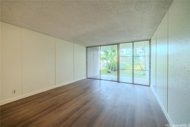 unfurnished room featuring expansive windows, a textured ceiling, and wood finished floors