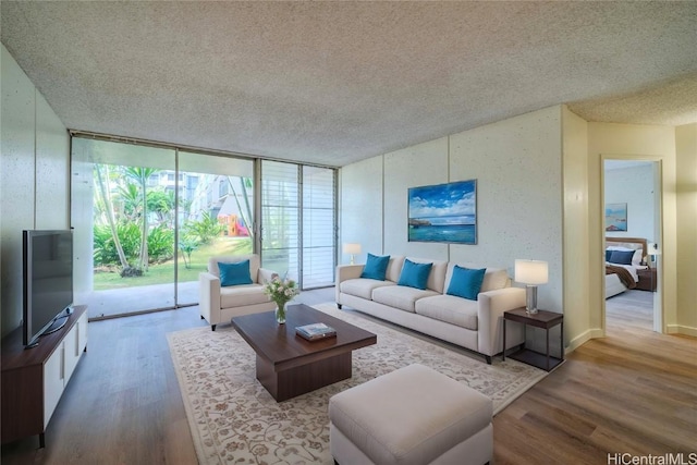 living room with a textured ceiling, a wall of windows, and wood finished floors