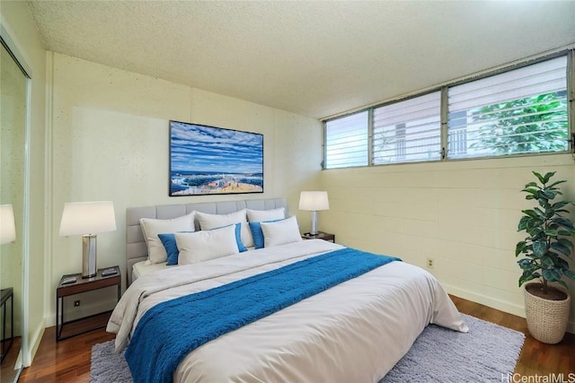 bedroom featuring a textured ceiling, wood finished floors, and concrete block wall