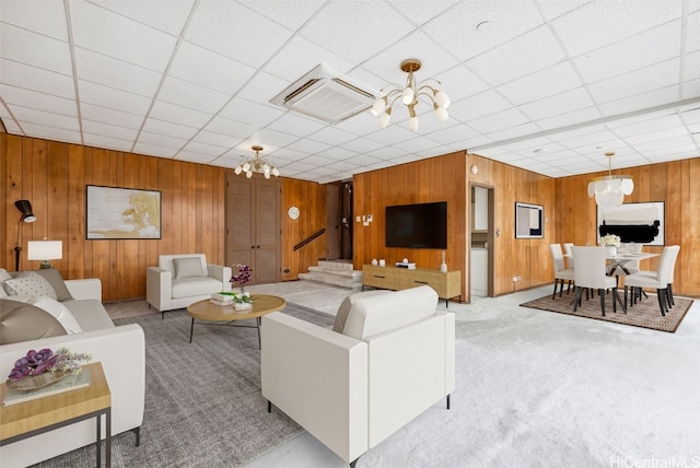 carpeted living area featuring wood walls and an inviting chandelier