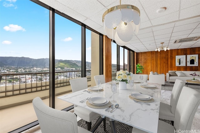 dining area featuring a paneled ceiling, visible vents, wood walls, and a mountain view