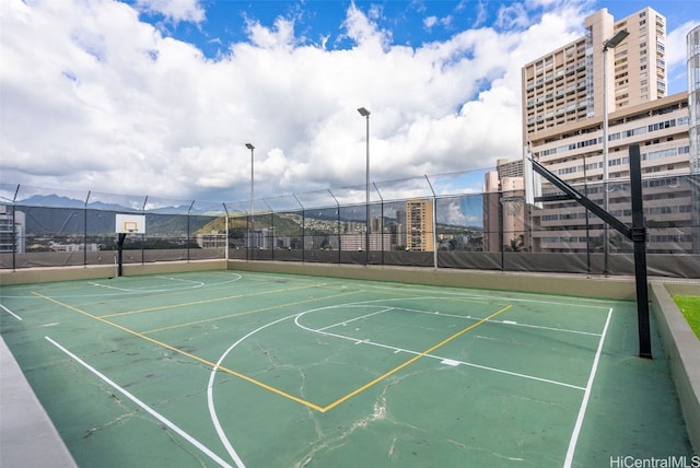 view of basketball court featuring community basketball court, fence, and a city view